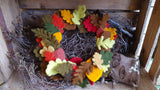 Autumnal wreath made from Needles felted leaves on a log with rustic wooden background
