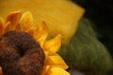 Felted sunflower closeup with wool batts in the background