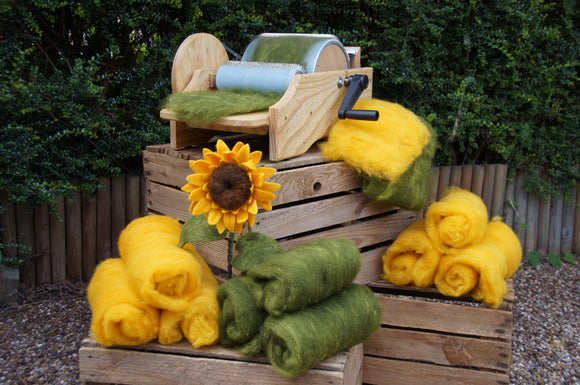 Needle felted sunflower with wool batts and carding machine on wooden crates