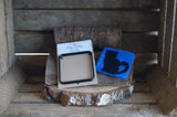 Sitting cat silhouette on a dark blue coaster with coaster template, in a rustic wooden backdrop